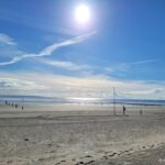 Ebbe und Flut auf Norderney: Gezeiten einfach erklaert Weiter Strand von Norderney bei Ebbe mit Spaziergängern