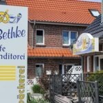 Bethke Norderney: Inselbäckerei, Konditorei und Café seit 1934 Werbestele und Gebäudeschild einer Filiale der Inselbäckerei Bethke auf Norderney (Foto von 2022)