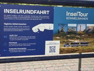 Infotafel der Bömmelbahn-Inselrundfahrt am Rosengarten auf Norderney mit Abfahrtszeiten und Route