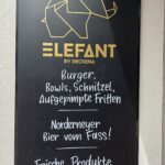 Elefant by Deckena Norderney: Burger und Klassiker aus eigener Fleischerei Elefant by Deckena auf Norderney – Konzepttafel mit Origami-Elefant: Burger, Bowls, Schnitzel, Norderneyer Bier vom Fass