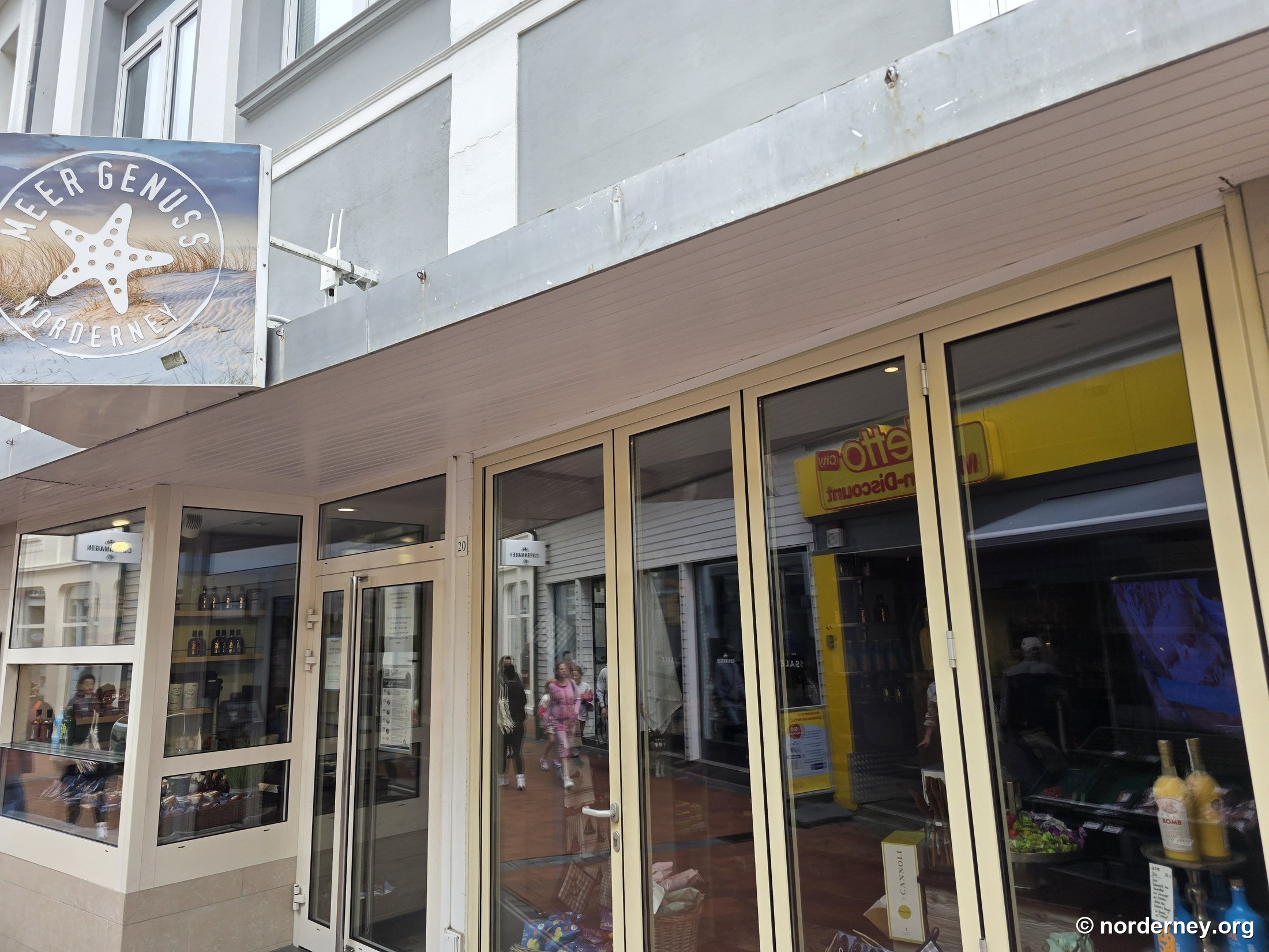 Auslegerschild „Meer Genuss Norderney“ am Deckena-Ladengeschäft in der Strandstraße 20