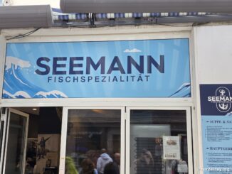 Seemann Fischspezialität in der Poststraße auf Norderney – Ladenfront mit Wellen-Logo, Anker-Emblem „Since 2025“ und Speisekarte im Schaufenster