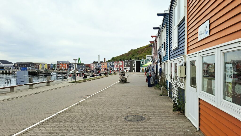 Bunte Hummerbuden an der Hafenstraße im Unterland von Helgoland mit Blick zum Hafen