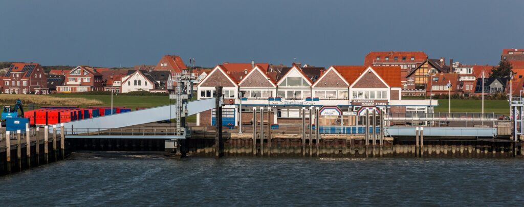 Fähranleger der Reederei Norden-Frisia im Hafen von Juist mit Inselort im Hintergrund