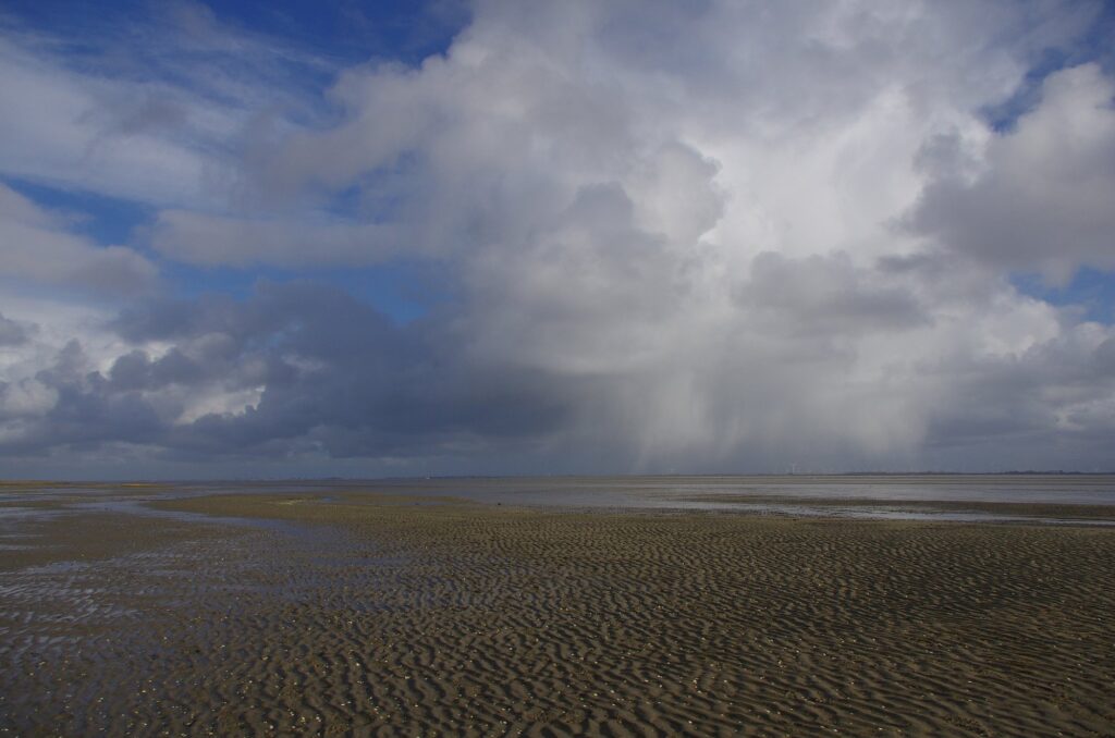 Trockengefallenes Watt mit Rippelmarken am Südstrand von Baltrum unter Schauerwolken