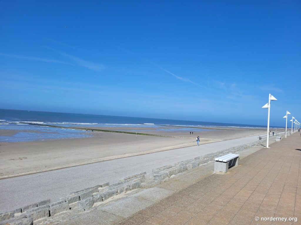 Strandpromenade von Norderney mit Bank und weißen Leuchten vor breitem Strand