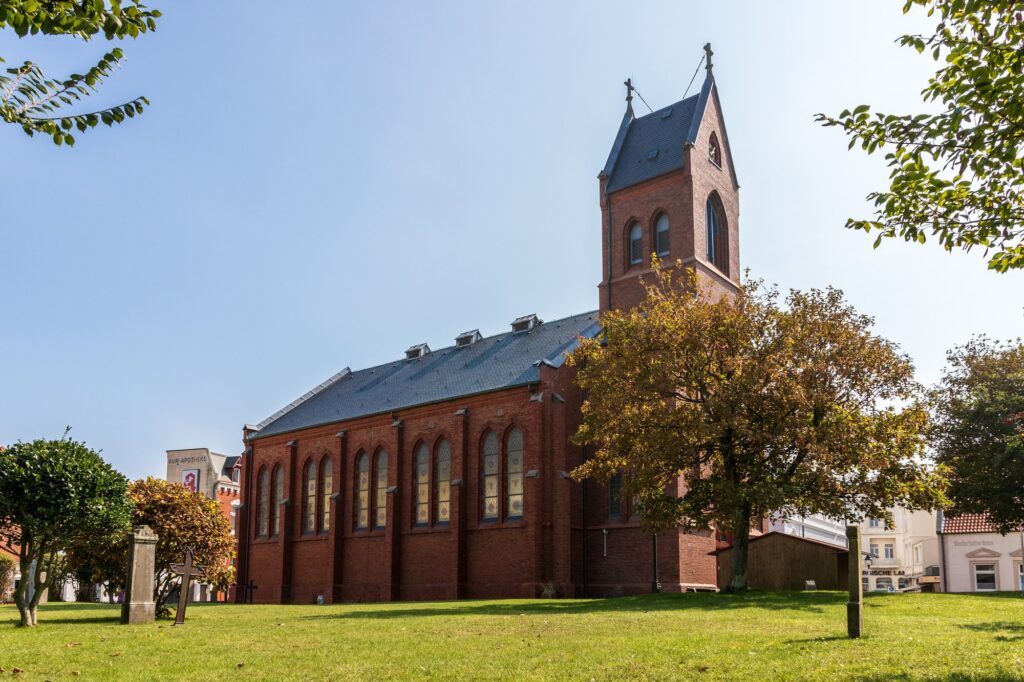 Evangelische Inselkirche an der Kirchstraße auf Norderney mit Kirchturm und Herbstbaum