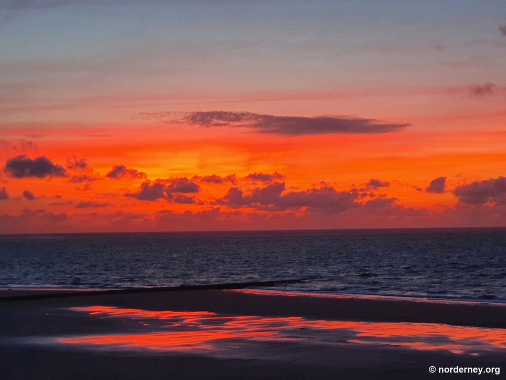 Glühendes Abendrot über der Nordsee spiegelt sich im nassen Strand von Norderney