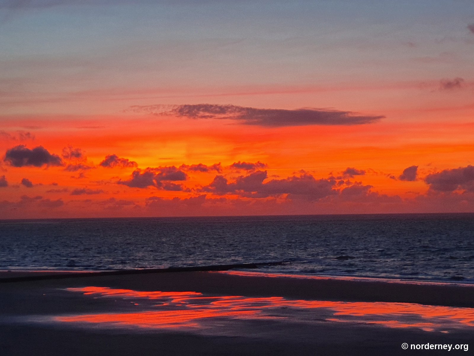 Rot leuchtender Abendhimmel über der Nordsee am Strand von Norderney