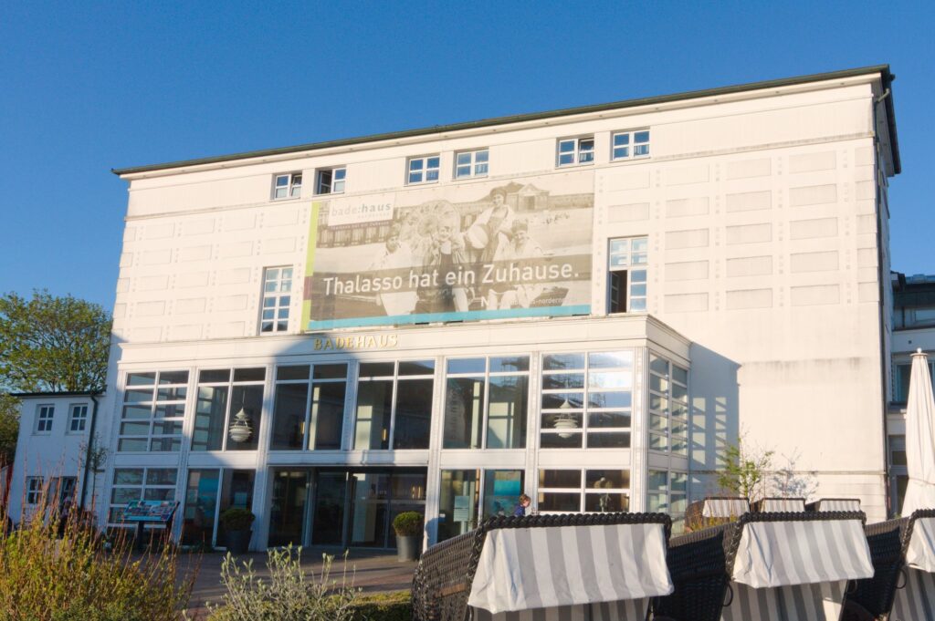 Fassade des bade:haus Norderney mit Schriftzug Badehaus über der Glasfront