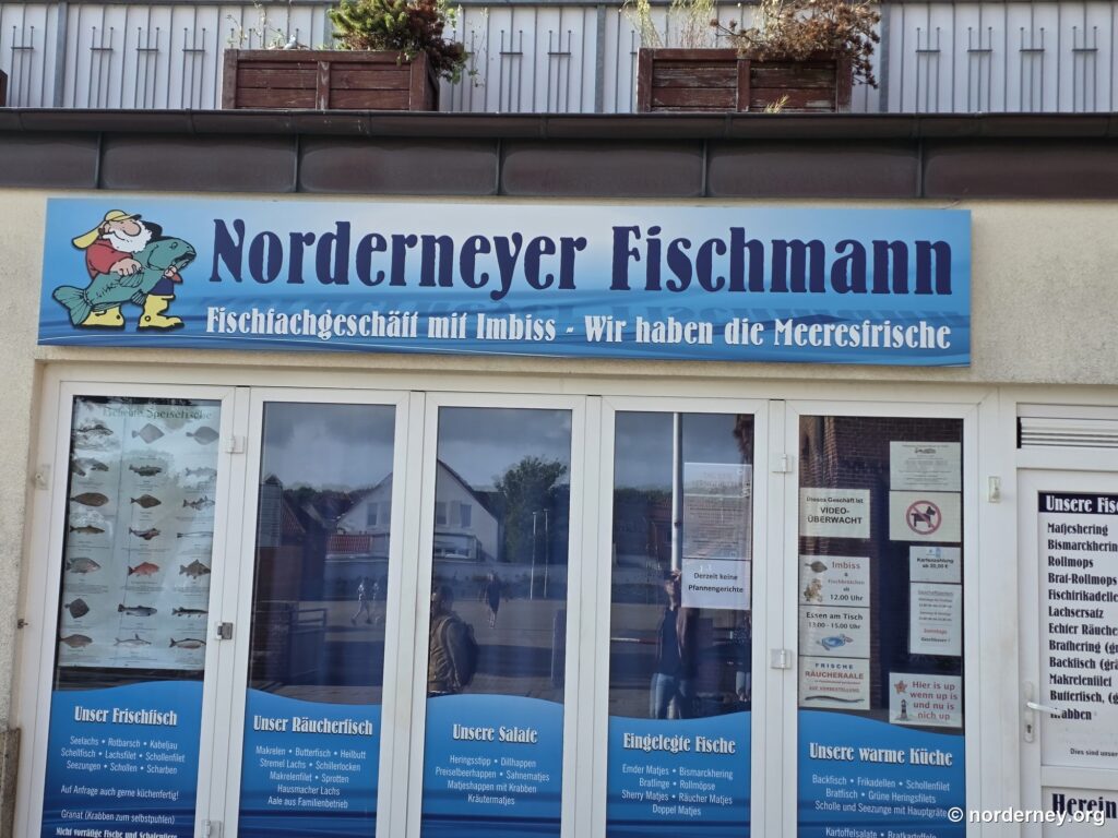 Schaufensterfront des Fischfachgeschäfts Norderneyer Fischmann mit Aushängen zu Frischfisch und Räucherfisch
