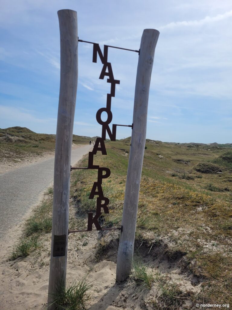 Schriftzug Nationalpark zwischen zwei Holzpfählen an einem Dünenweg auf Norderney